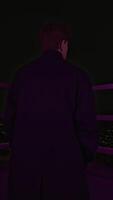 Young man stands on roof of building at night. Media. Handsome man in coat is standing on roof of high-rise building. Photo shoot of man on roof of high-rise building video