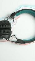 Headphones on white background with animated lines. Animation. Headphones frame moving colored lines on white background. Real headphones on background of repeating shape of animated lines video