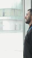 Office worker looks at snow. Media. Businessman frowns at falling snow through panoramic Windows. Office worker looks at snowfall outside window video