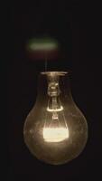 Close up of light bulb turns on and off. Footage. Blinking old fashioned light bulb on a dark room background. video