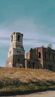 An ancient stone church building on blue cloudy sky background. . Bottom view of a red brick old building and autumn trees and a meadow. video