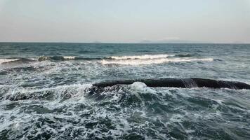 Waves crash over rocks in a serene ocean setting, symbolizing tranquility and coastal getaways video