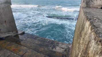 Waves crash against a stone seawall on a cloudy day, evoking concepts of tranquility and nature video