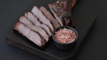Grilled wagyu beef tomahawk steak with salt, spices and herbs on a dark concrete background video