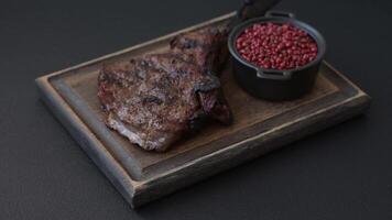 Grilled wagyu beef tomahawk steak with salt, spices and herbs on a dark concrete background video