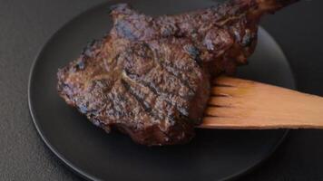 Grilled wagyu beef tomahawk steak with salt, spices and herbs on a dark concrete background video