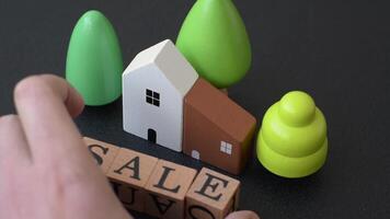 A small wooden house and keys as an idea for investing in your own home and achieving the goal of buying real estate. Background for your idea video
