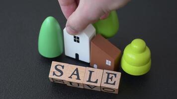 A small wooden house and keys as an idea for investing in your own home and achieving the goal of buying real estate. Background for your idea video