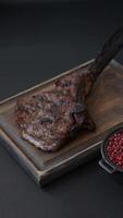 Grilled wagyu beef tomahawk steak with salt, spices and herbs on a dark concrete background video