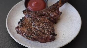 Grilled wagyu beef tomahawk steak with salt, spices and herbs on a dark concrete background video