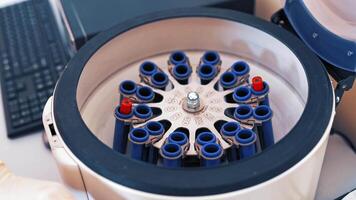 Female scientist loads some vials of liquid into a centrifuge in a laboratory. Close-up hands in protective gloves of a female placing blood samples in the special machine and switches it on. video