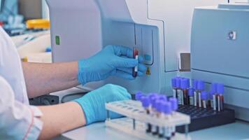 Close-up of female hands filling the tube with blood from the automated machine. Technician uses laboratory equipment while working with samples in tubes indoors. video