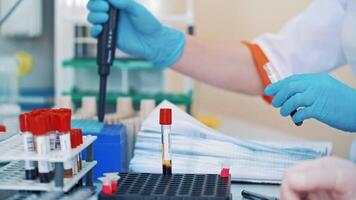 Medical nurse in blue protective gloves uses laboratory equipment in clinic. Hands of a laboratory technician are working with samples in tubes on a table. video