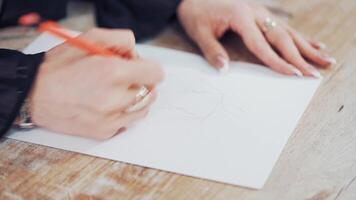 Female's hands drawing sketches of clothes on paper in her workplace. Clothes designer or tailor sketching with a pencil on a table. video