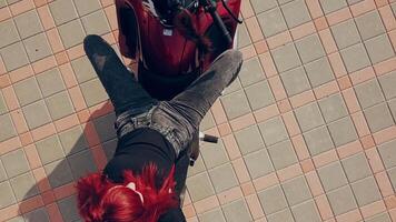 Red-haired young woman sitting on a red motorcycle and lying on it over the background of paving tile. Camera moves up. video