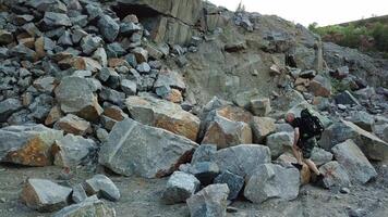 Natural background of a rocky place and a tourist climbing in summer. Hiker walking over the large pile of stones in a mountainous area. video