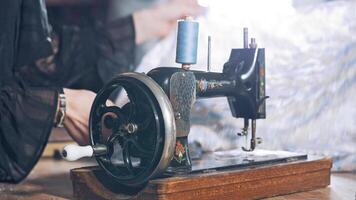 Old black sewing machine on the background of a female tailor at work in atelier. Professional seamstress working in the workshop with beautiful material. video