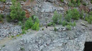 Top view of an active tourist walking on the canyon with stone surface in summer. Male traveller hiking in the mountains near the lake outside. video