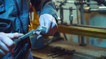 Mechanic is working with metal in a workshop, making measurements of metal parts. Worker holds a caliper in his hand, in a special suit on factory background. video