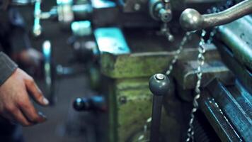 Machine operator turns on an industrial machine. Man employee working with turning lathe and metalworking machine at manufacturing hall at industrial factory video