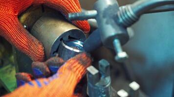 Professional machinist puts metal instruments to the machine. Man's hands operating lathe grinding machine metalworking industry concept. Close-up video
