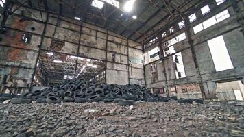 Big old empty factory with garbage and a pile of used rubber tyres inside. Tires that are no longer suitable for use on vehicles in a damaged plant. video