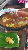 The Gado-gado trader is preparing many orders that are processed in big stone mortar. Gado-gado is a food consisting of vegetables,potatoes,tempeh,tofu,boiled eggs and then seasoned with peanut sauce. video