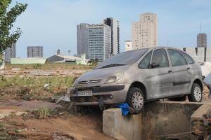 VALENCIA, SPAIN OCTOBER 31, 2024. Muddy car sits precariously on a concrete block amidst flood debris in Valencia, highlighting the devastation caused by the natural disaster photo