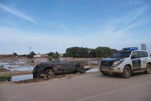 VALENCIA, SPAIN OCTOBER 31, 2024. Devastating consequences of flooding in Valencia, Spain, showing damaged car and police vehicle photo