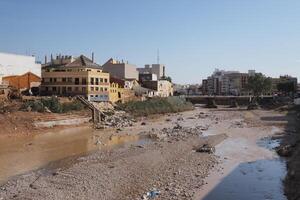 VALENCIA, SPAIN OCTOBER 31, 2024. Riverbed filled with debris and mud after a severe flood in Valencia, highlighting the devastating impact of natural disasters on urban areas photo