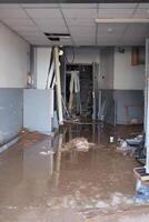 VALENCIA, SPAIN OCTOBER 31, 2024. Muddy water flooding a damaged commercial building interior in Valencia after a severe flood, showing the devastating impact of natural disasters photo
