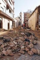 VALENCIA, SPAIN OCTOBER 31, 2024. Volunteers assessing the damage caused by floods in Valencia, with rubble and debris filling streets and damaged buildings photo