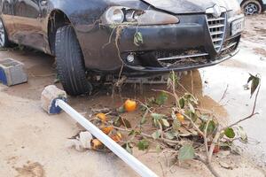 VALENCIA, SPAIN OCTOBER 31, 2024. Car damaged by floodwaters, surrounded by debris including branches and fruit, highlighting the devastating impact of natural disasters photo