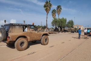 VALENCIA, SPAIN OCTOBER 31, 2024. An off road vehicle covered in mud navigates a street covered in debris and mud in the aftermath of severe flooding in Valencia, Spain photo
