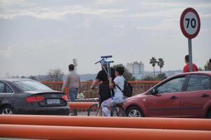 VALENCIA, SPAIN OCTOBER 31, 2024. Cleaners riding bicycle and carrying cleaning supplies on bridge after flood in Valencia, Spain photo
