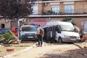 VALENCIA, SPAIN OCTOBER 31, 2024. Rescue worker assessing the damage after a severe flood in Valencia, Spain, with overturned cars and fallen trees photo