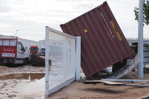VALENCIA, SPAIN OCTOBER 31, 2024. Floodwaters causing significant damage to an industrial area in Valencia, leaving a fallen intermodal container and mud photo