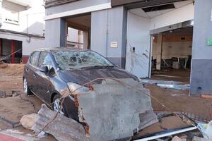 VALENCIA, SPAIN OCTOBER 31, 2024. A damaged car and building show the devastating aftermath of flooding in Valencia, Spain photo