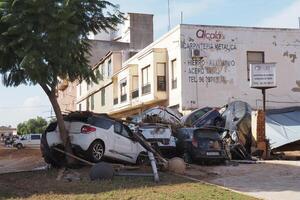 VALENCIA, SPAIN OCTOBER 31, 2024. Wrecked cars piled up against a tree and building after severe flooding in Valencia, Spain, highlighting the destructive impact of climate change photo