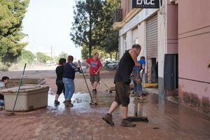 VALENCIA, SPAIN OCTOBER 31, 2024. Citizens cleaning mud and debris in front of their shops after a devastating flood in Valencia, Spain photo