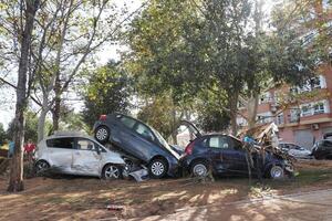 VALENCIA, SPAIN OCTOBER 31, 2024. Aftermath of a severe flood showing damaged vehicles piled up against trees in a residential area of Valencia photo