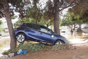 VALENCIA, SPAIN OCTOBER 31, 2024. Aftermath of flooding in Valencia, Spain, showing a car leaning against a tree, highlighting the devastating impact of the natural disaster photo
