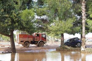 VALENCIA, SPAIN OCTOBER 31, 2024. Firefighters driving on a flooded road next to a stranded car, showing the aftermath of a natural disaster in Valencia photo