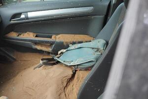 VALENCIA, SPAIN OCTOBER 31, 2024. Muddy backpack resting on car seat, showing devastation after severe flooding in Valencia photo