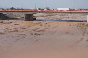 VALENCIA, SPAIN OCTOBER 31, 2024. Muddy flood water covers the riverbed and creates a dangerous situation under a highway bridge in Valencia, Spain photo
