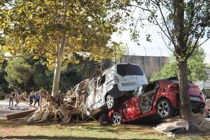 VALENCIA, SPAIN OCTOBER 31, 2024. Cars piled up against trees after heavy flooding in Valencia, Spain, highlighting the devastating impact of natural disasters photo