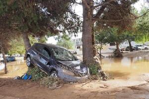 VALENCIA, SPAIN OCTOBER 31, 2024. Devastating consequences of flooding in Valencia, with a damaged car leaning against a tree photo