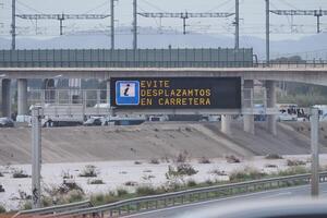 VALENCIA, SPAIN OCTOBER 31, 2024. Flooded fields reaching a highway sign recommending avoiding travel by road, showing the devastating consequences of the flooding in Valencia photo