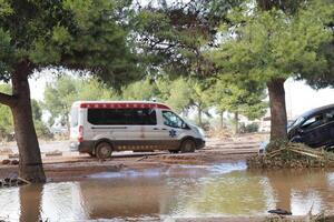 VALENCIA, SPAIN OCTOBER 31, 2024. Paramedics driving ambulance on flooded road, providing emergency medical services after heavy rain and flood in Valencia photo