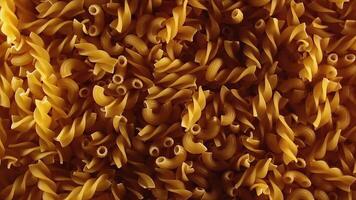 Uncooked Fusilli and Chifferi Rigati Pasta - Top View, Low Key Light. Fat and Unhealthy Food. Classic Dry Macaroni, Slowly Rotating Background. Raw Different Macaroni Pasta Texture - Rotate Left video